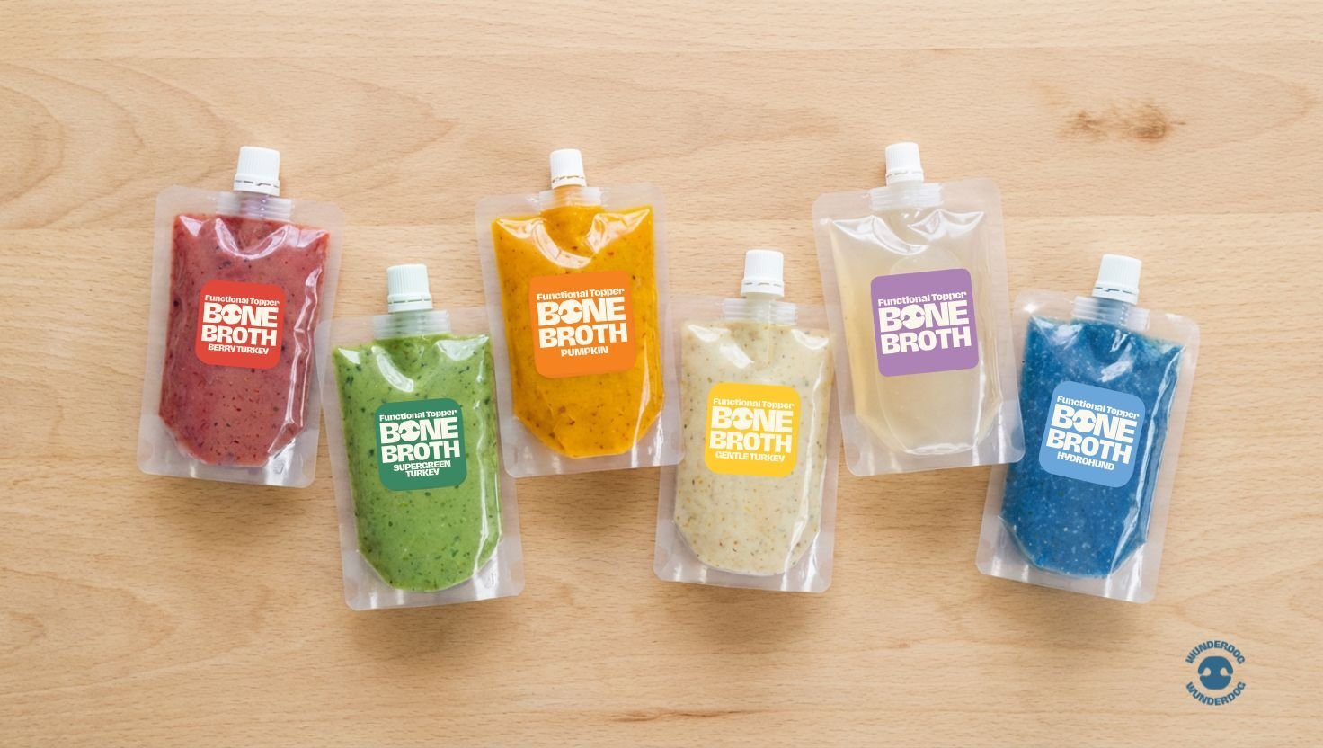 Assorted Wunderdog functional toppers in pouches arranged on a wooden background.